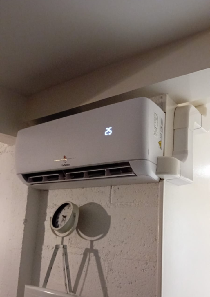 Unité intérieure murale de pompe à chaleur air/air installée dans une pièce, avec affichage digital de température.